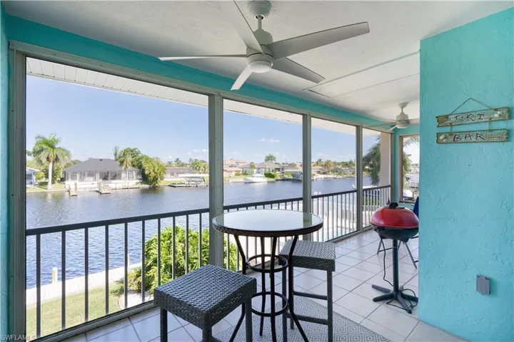 Sunroom / solarium featuring a textured wall, a water view, tile patterned flooring, and a residential view