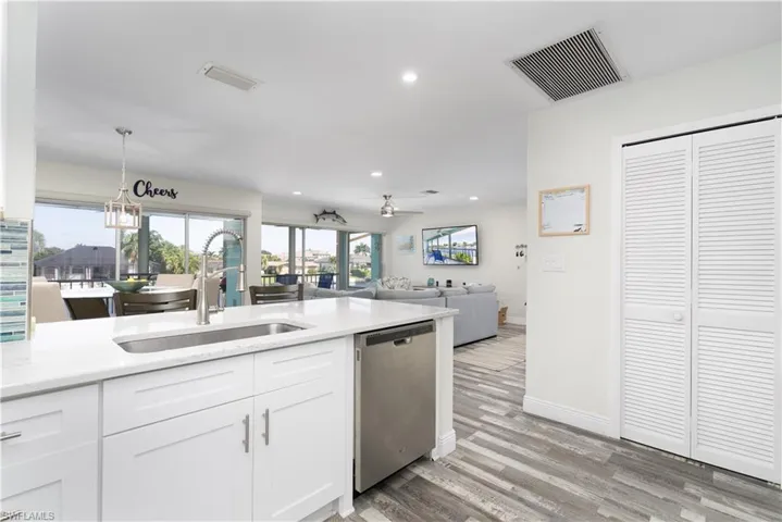 Kitchen with recessed lighting, white cabinets, healthy amount of natural light, dishwasher, and light stone countertops