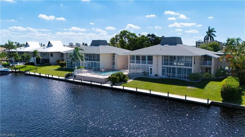 Back of property featuring a lawn, a water view, and an outdoor pool