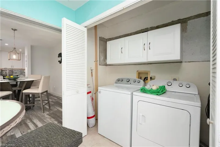 Washroom featuring cabinet space, separate washer and dryer, light tile patterned flooring, and recessed lighting
