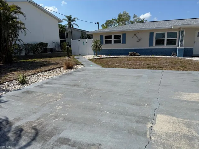 View of front of property featuring brick siding, fence, and stucco siding