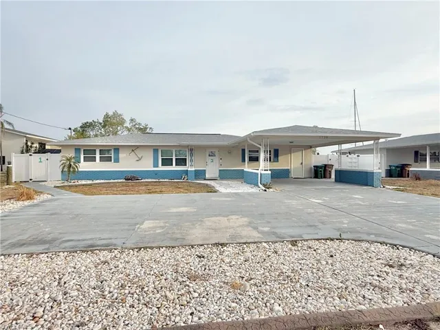 View of front facade featuring concrete driveway, a carport, stucco siding, and fence