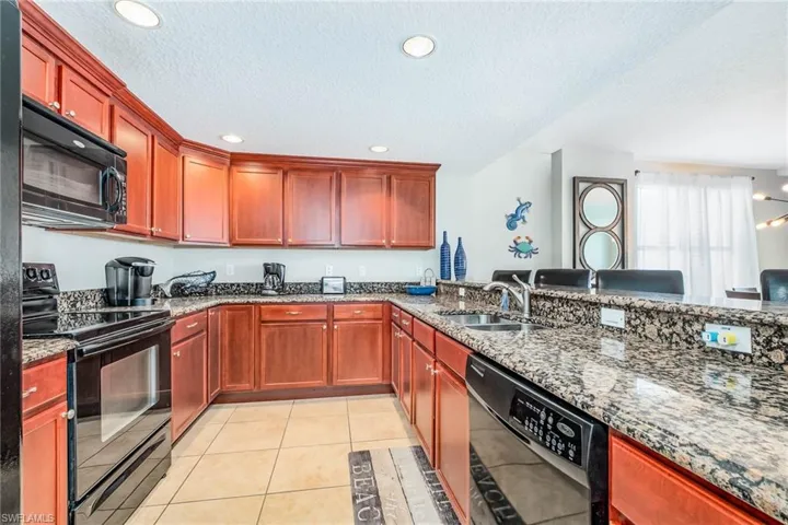 Kitchen with black appliances, dark stone countertops, a textured ceiling, light tile patterned floors, and recessed lighting