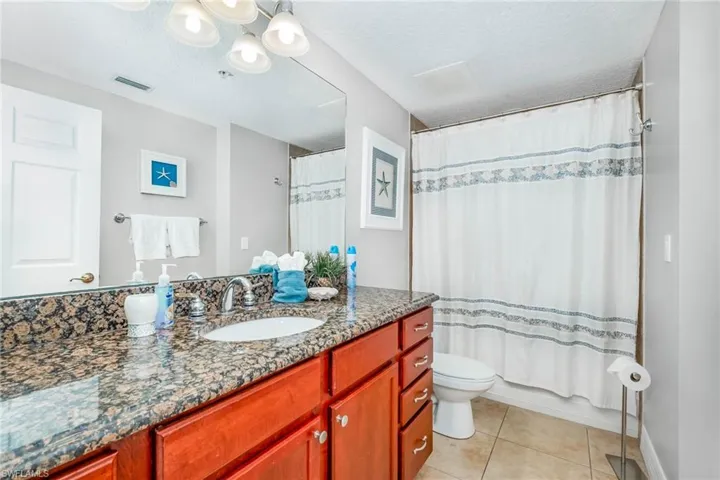 Bathroom featuring a textured ceiling, vanity, light tile patterned floors, and shower / bath combo