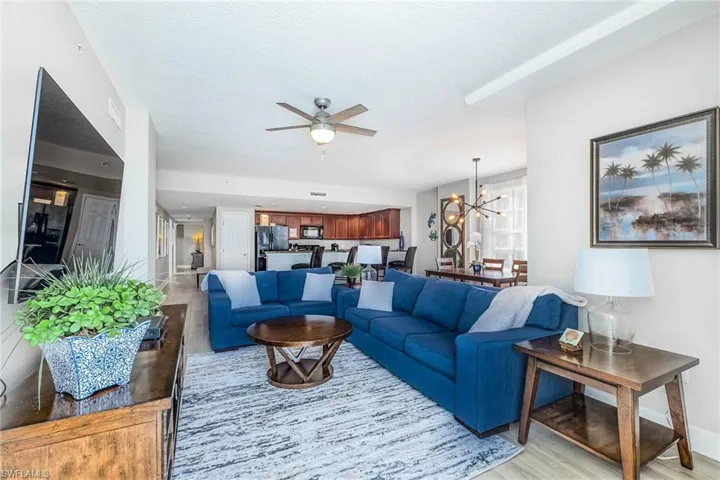 Living area with a chandelier, light wood finished floors, a ceiling fan, and a textured ceiling