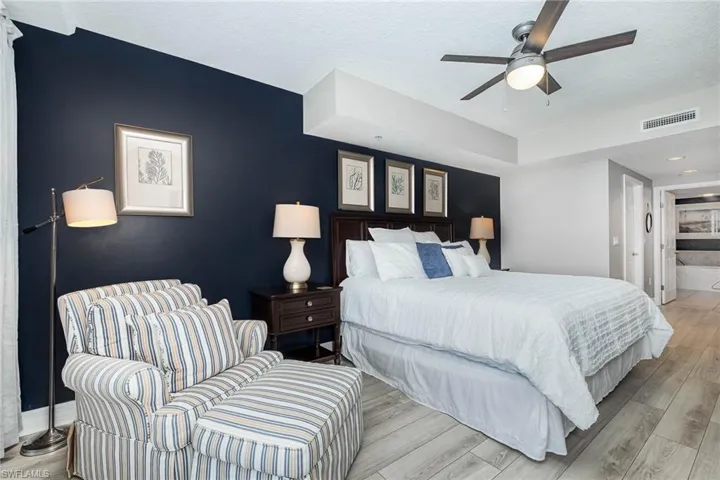 Bedroom with light wood-style floors, ceiling fan, a textured ceiling, and connected bathroom
