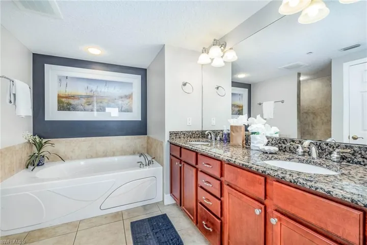 Bathroom with a garden tub, double vanity, light tile patterned floors, and a textured ceiling