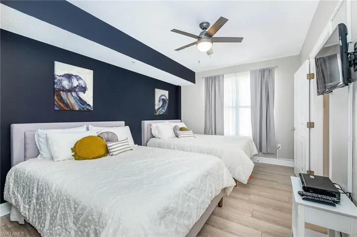 Bedroom featuring light wood-style floors, ceiling fan, and an accent wall