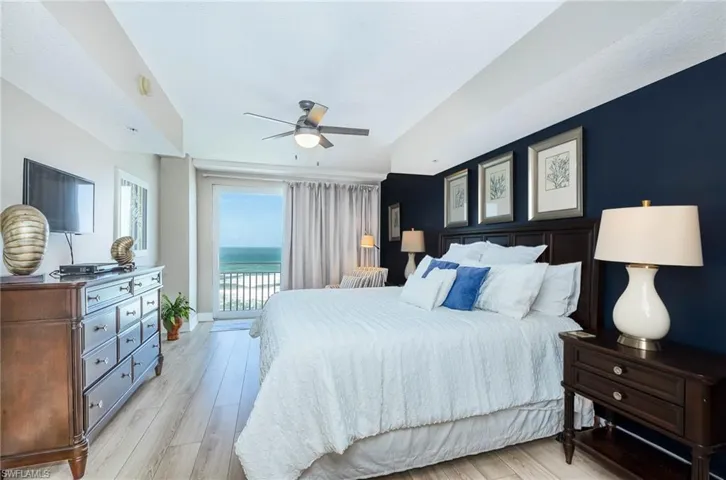 Bedroom with access to exterior, light wood-style flooring, a ceiling fan, and a water view