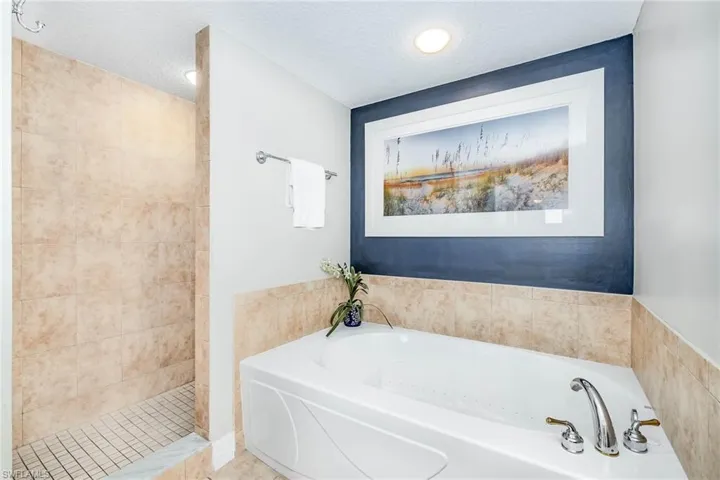Full bathroom with a bath, a textured ceiling, tiled shower, and recessed lighting