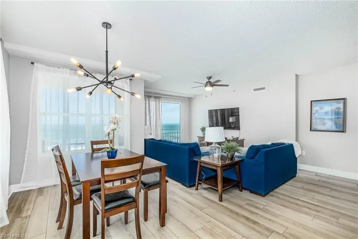 Dining room with a textured ceiling, light wood finished floors, a ceiling fan, and a chandelier