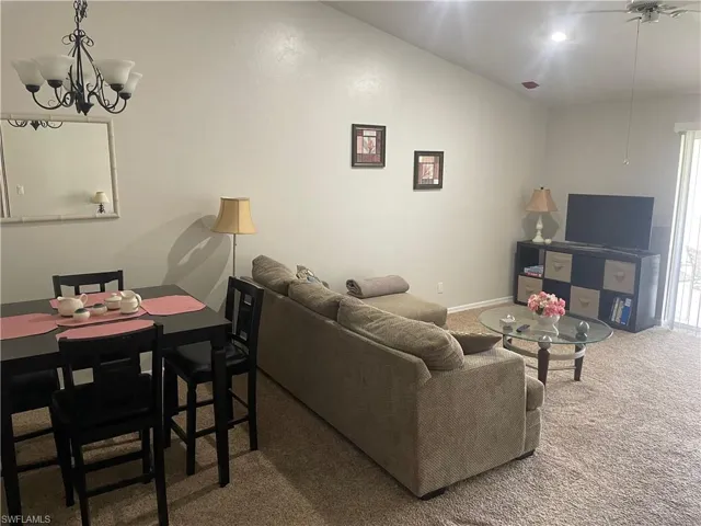 Carpeted living area featuring hanging lights and ceiling fan