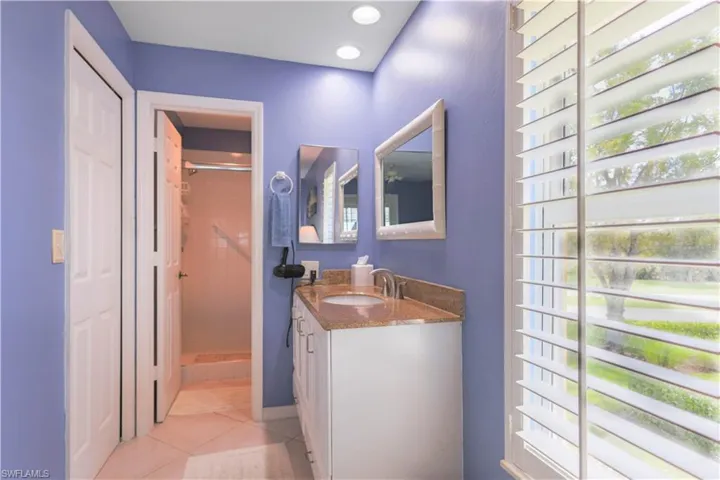 Bathroom featuring walk in shower, vanity, and tile patterned floors