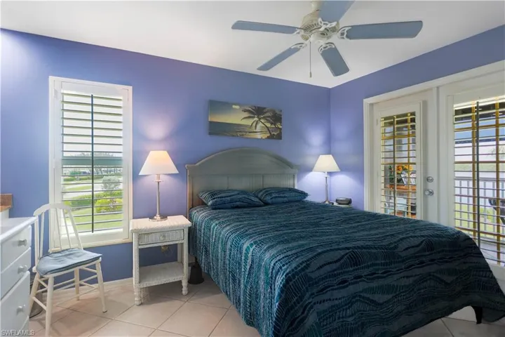 Tiled bedroom featuring ceiling fan, access to exterior, and multiple windows