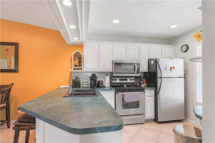 Kitchen featuring white cabinets, sink, kitchen peninsula, stainless steel appliances, and a breakfast bar area