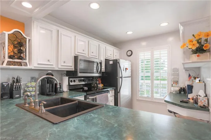 Kitchen with white cabinetry, sink, and stainless steel appliances