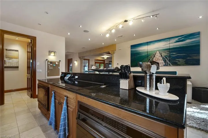 Breakfast bar featuring stainless steel oven, dark stone countertops, light tile%