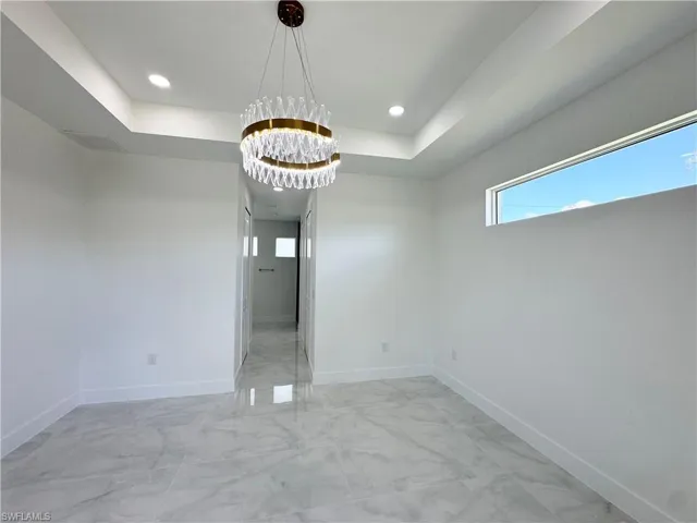 Unfurnished room with a tray ceiling, a chandelier, and recessed lighting