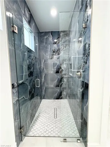 Bathroom featuring a marble finish shower and tile patterned flooring