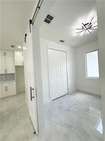 Corridor featuring light marble finish flooring and a barn door
