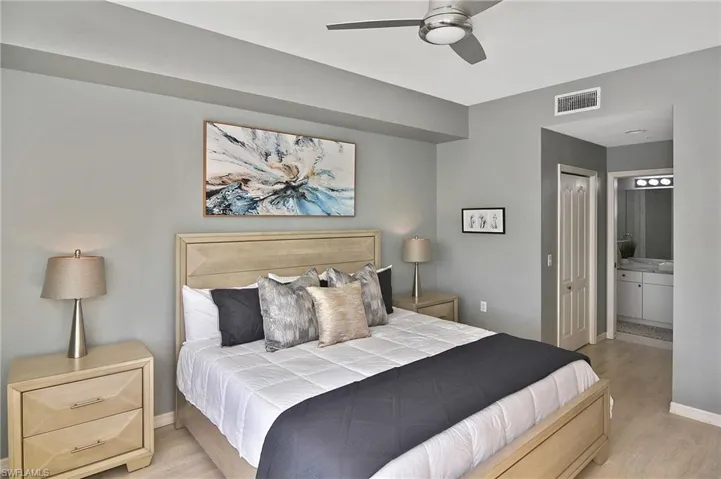 Bedroom with light wood-style flooring, connected bathroom, a ceiling fan, and a closet