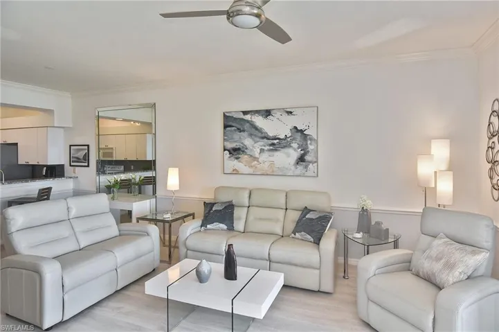 Living room with crown molding, wood finished floors, and a ceiling fan