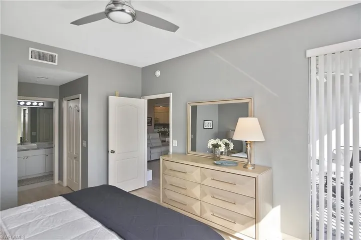 Bedroom featuring ensuite bath, ceiling fan, and light wood-type flooring
