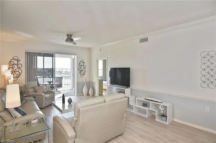 Living area featuring wood finished floors, ceiling fan, and crown molding