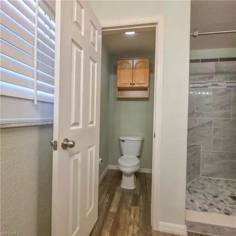 Bathroom featuring a stall shower, dark wood-style floors, and a textured wall