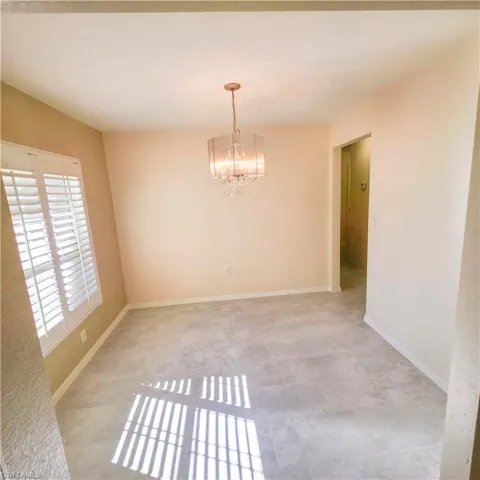 Spare room featuring a chandelier and baseboards