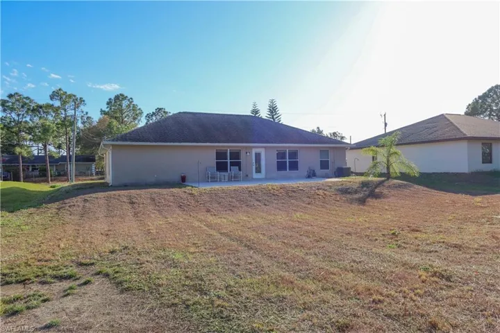 Back of property with a yard, a patio area, and stucco siding