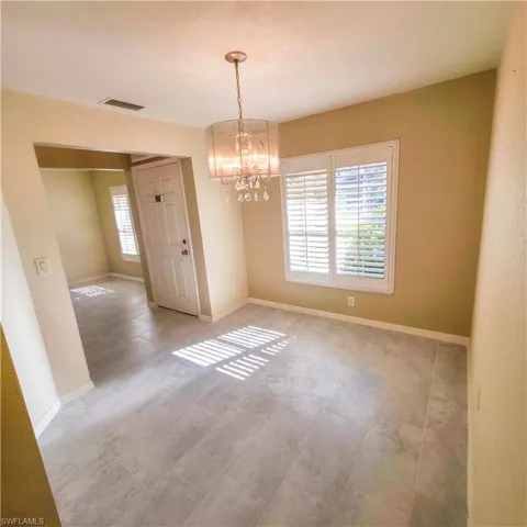 Unfurnished dining area with a chandelier and plenty of natural light looking at front door