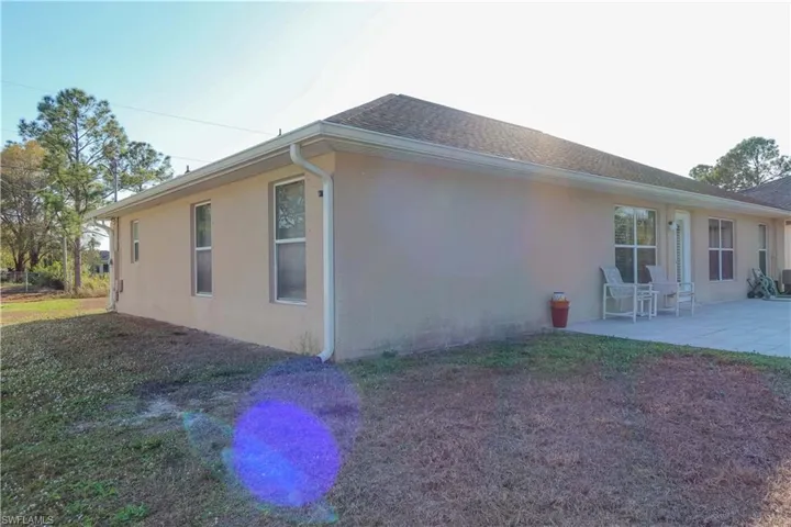 View of home's exterior with stucco siding, a patio area, and a lawn
