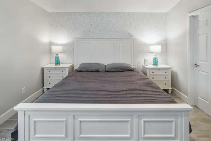 Bedroom featuring an accent wall, wallpapered walls, and light wood-type flooring