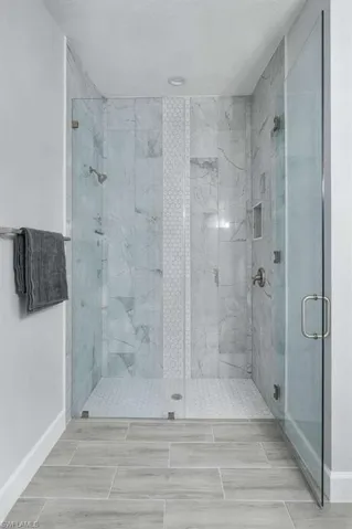 Full bathroom with a marble finish shower and baseboards