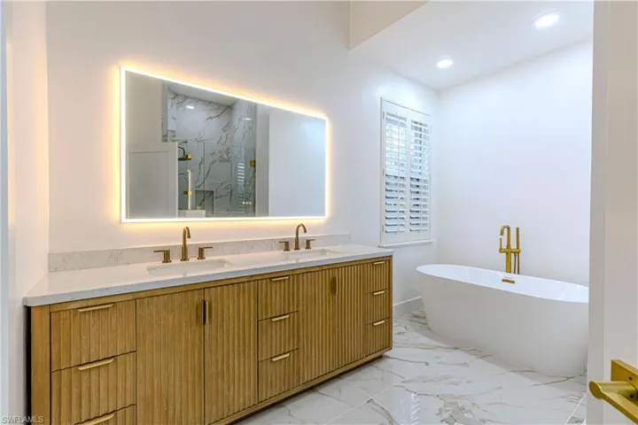 Primary Bathroom with a soaking tub, marble finish flooring, double vanity, a marble finish shower, and recessed lighting