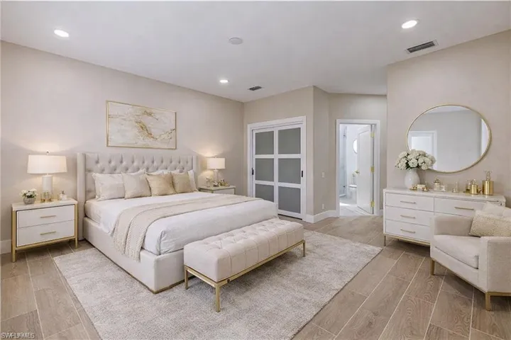 Bedroom with light wood-style flooring, ensuite bath, and recessed lighting