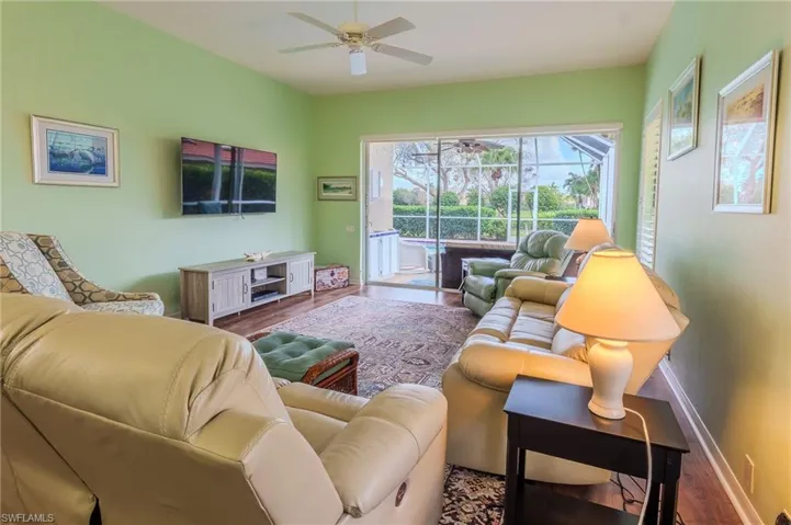 Living room featuring ceiling fan, wood finished floors, and a sunroom