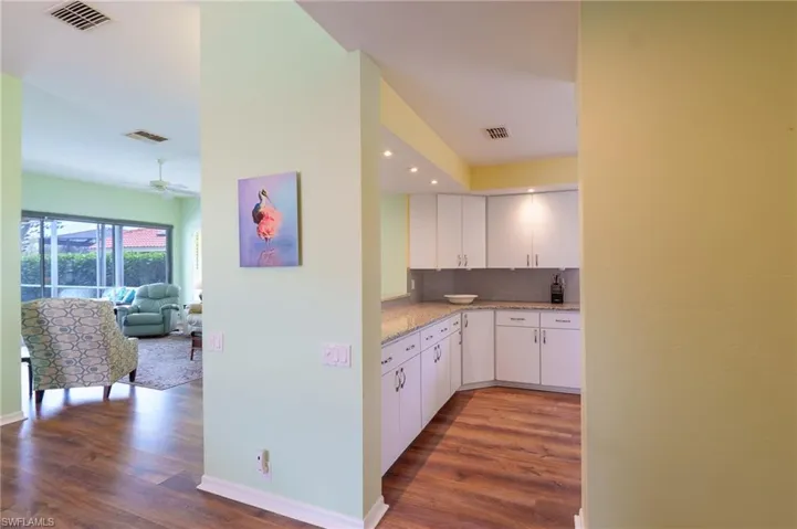 Kitchen featuring decorative backsplash, dark wood-style flooring, white cabinets, and light stone countertops