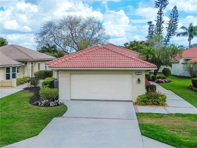 View of front of house with a front yard, a garage, a tile roof, and stucco siding