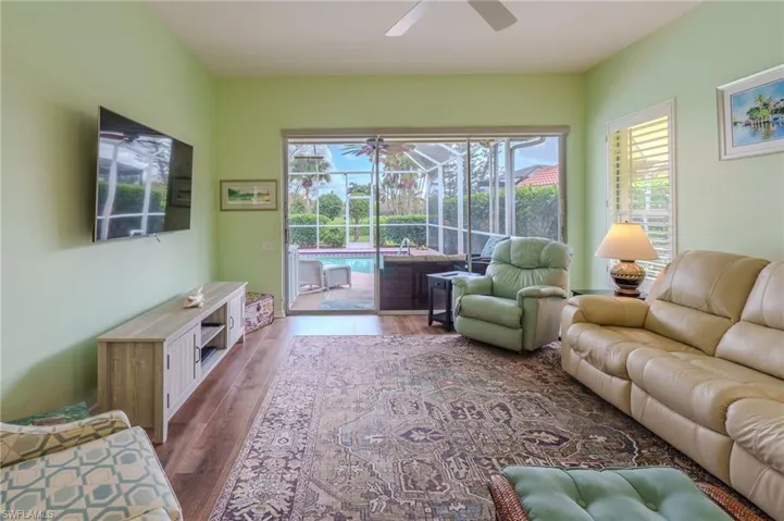 Living room with a sunroom, a ceiling fan, and dark wood-style floors