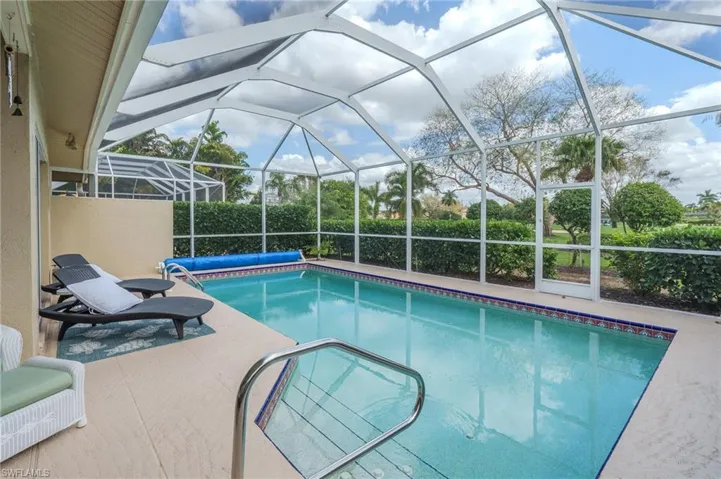 Outdoor pool featuring a sunroom, glass enclosure, and a patio