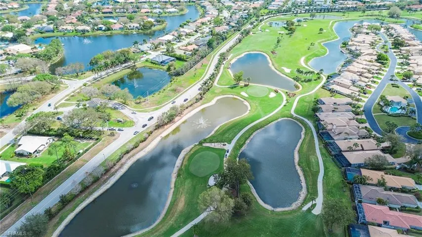 Aerial view of property and surrounding area featuring nearby suburban area, a large body of water, and a golf club