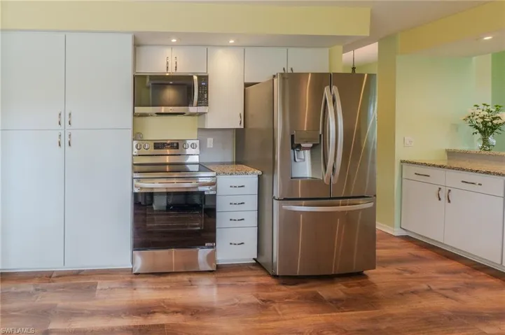 Kitchen with stainless steel appliances, white cabinetry, dark wood finished floors, and recessed lighting