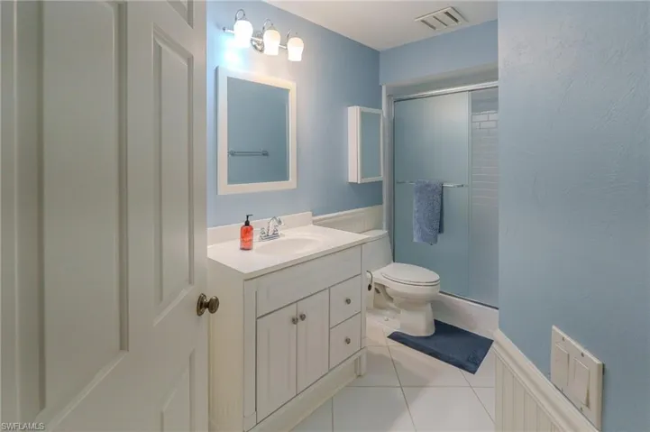 Bathroom with vanity, light tile patterned flooring, a shower stall, and a wainscoted wall