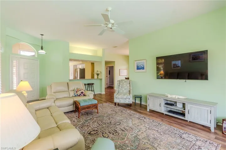 Living area featuring ceiling fan and dark wood-style flooring