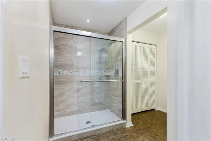 Bathroom featuring parquet floors and a shower with door
