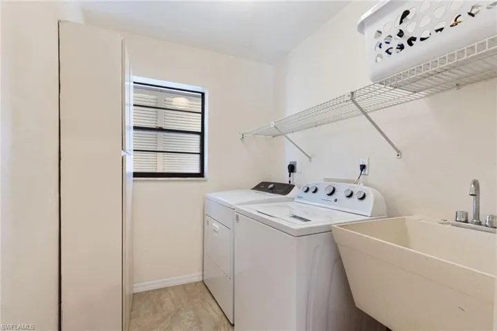 Washroom featuring washing machine and clothes dryer, sink, and light hardwood / wood-style flooring