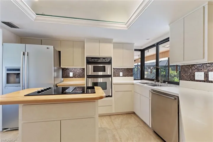Kitchen featuring sink, stainless steel appliances, a raised ceiling, and a kitchen island