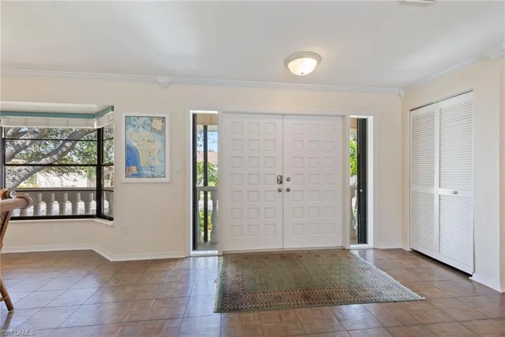 Foyer featuring crown molding, dark parquet flooring, and a wealth of natural light